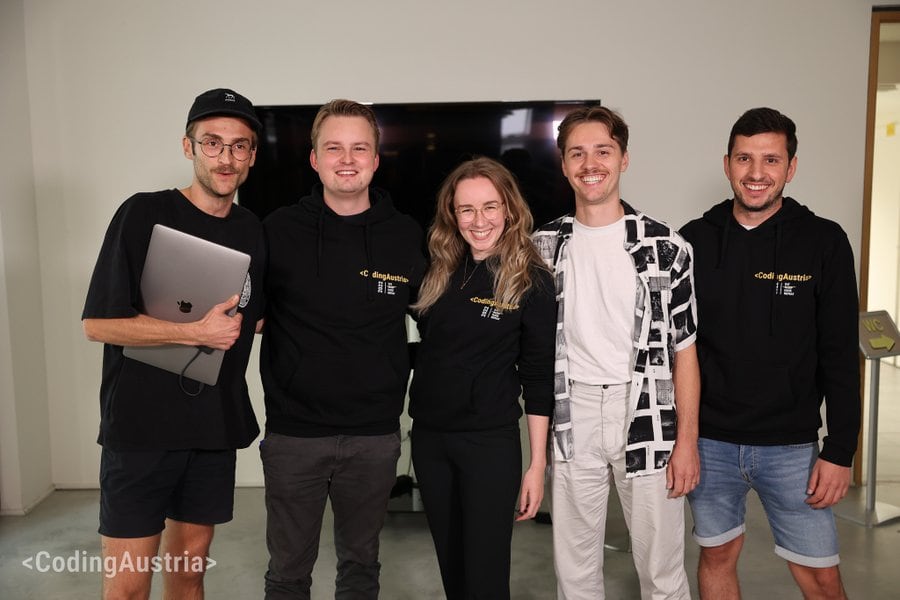 A group of five people aged around 25. Four are men and one is a woman. Thea are smiling.