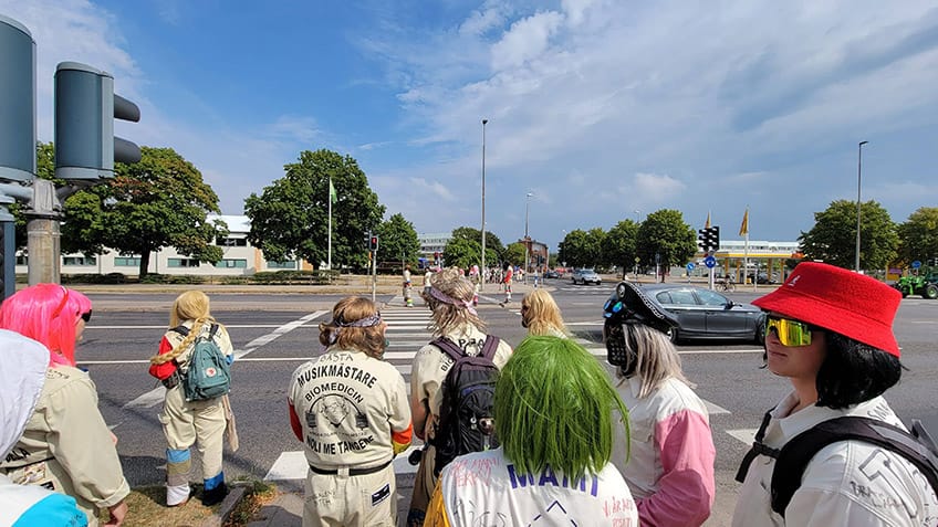 People dressed up with colourful wigs, masks and overalls, walking over as street.